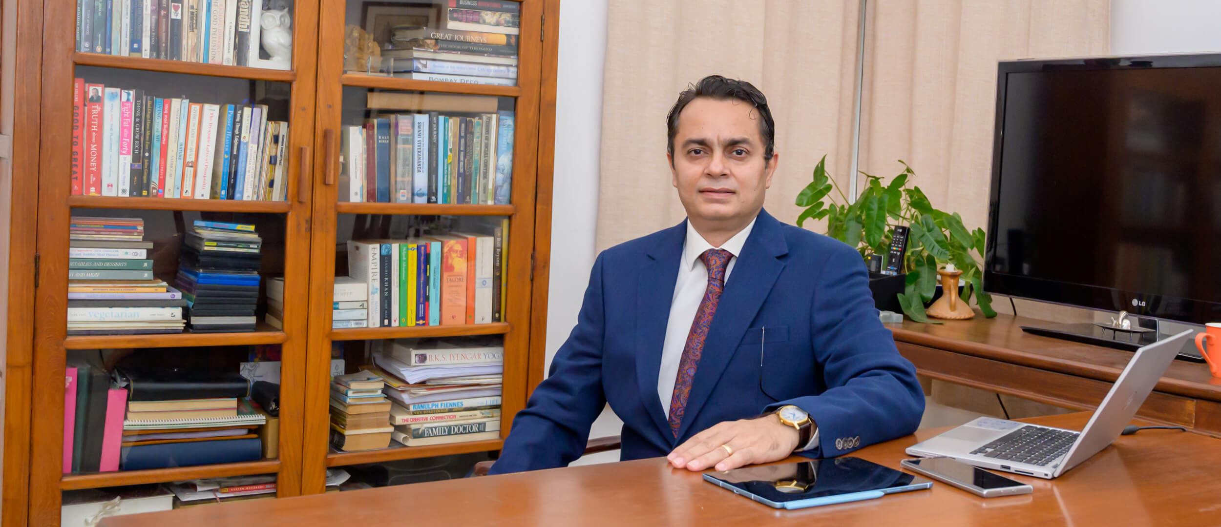 Arjun Khanna seated at his desk in front of a wall of books